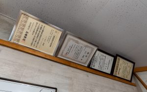 職人の皆さんの賞状が並ぶ事務所内